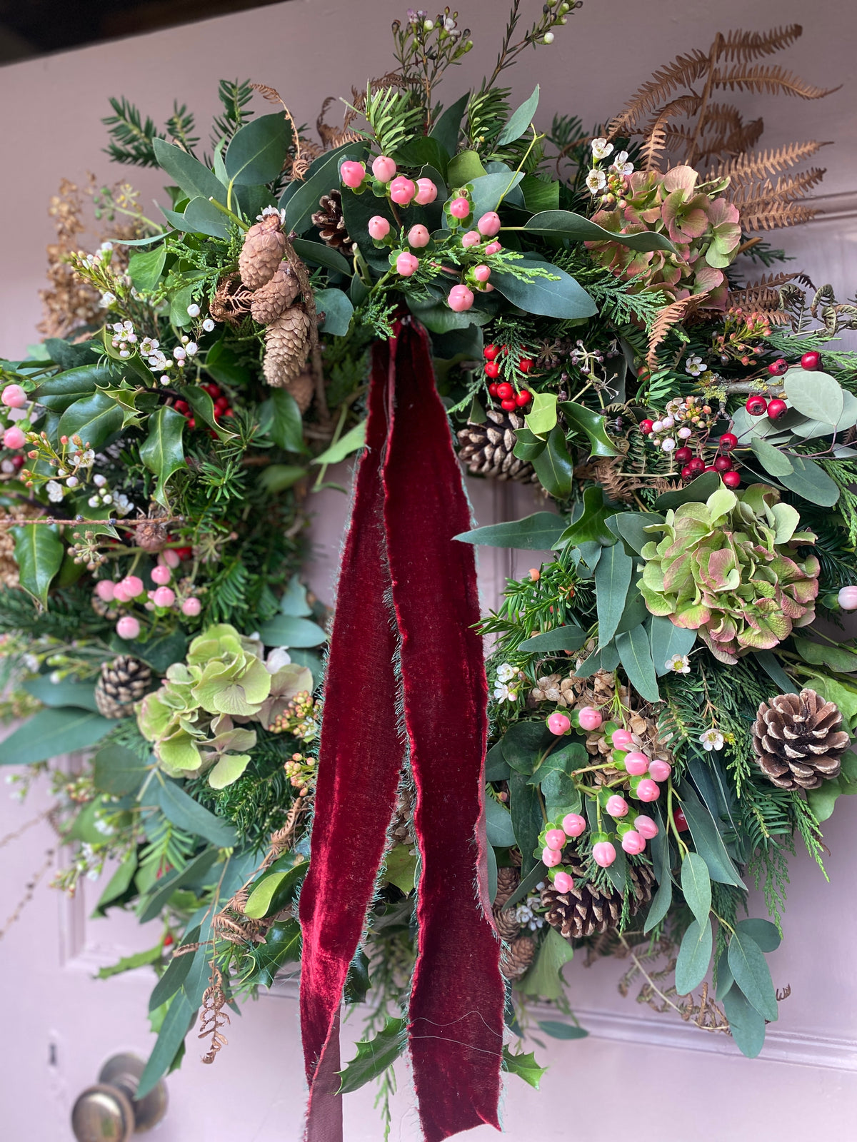 A lush and luxurious Christmas wreath. Pre made for you to decorate your door this season. Soft velvety ribbon, beautiful seasonal foliage, pine cones and berries. 