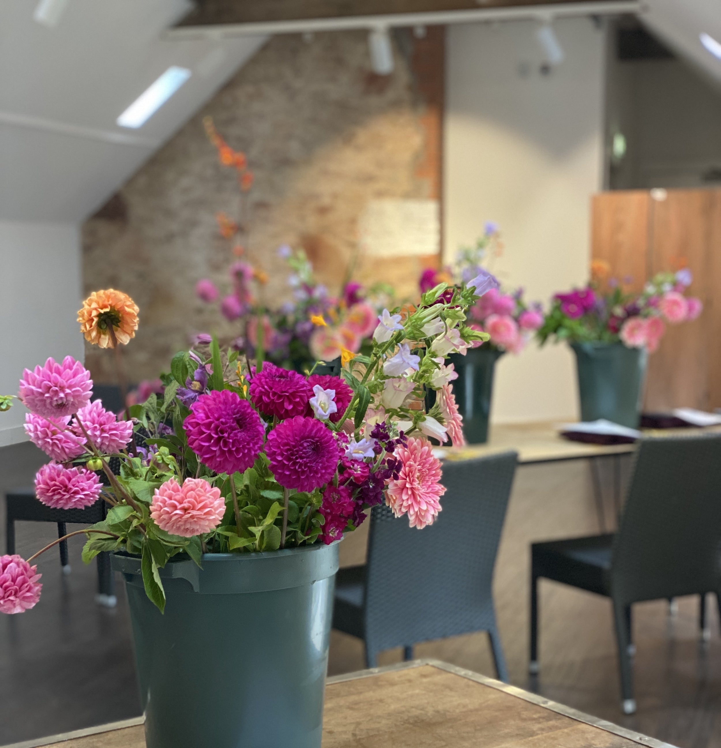 Floral arrangement in a pot on a table with scissors and paper in a room setting.